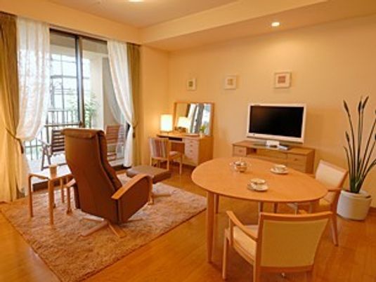 広めの部屋のリビングルーム。テレビやリラックス用チェア、テーブルがある
