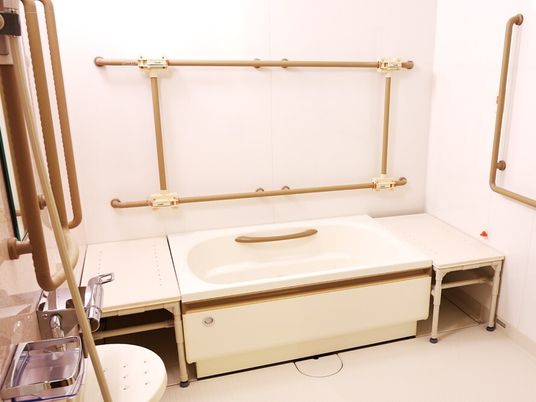 たくさんの手すりが設置された浴室。浴槽の両サイドにはベンチがあり、シャワースペースもある。