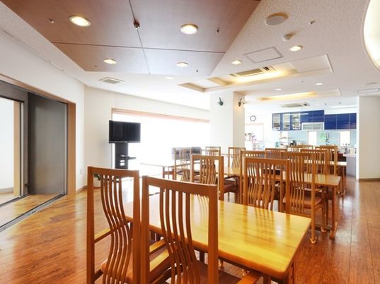 木製の椅子とテーブルが並べられている施設内のリビングスペースの様子