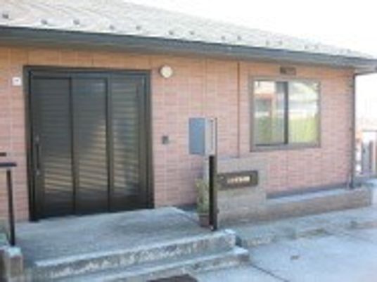 平屋建ての建物はブラウンを基調としたすっきりとしたデザイン。玄関にはポストが置かれている。