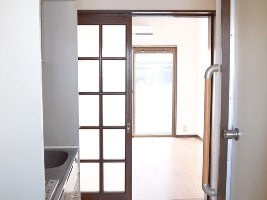 キッチン付きの居室にはエアコンも付き、フローリングのフロアが広がっている。キッチンとリビングの間にはドアがある。