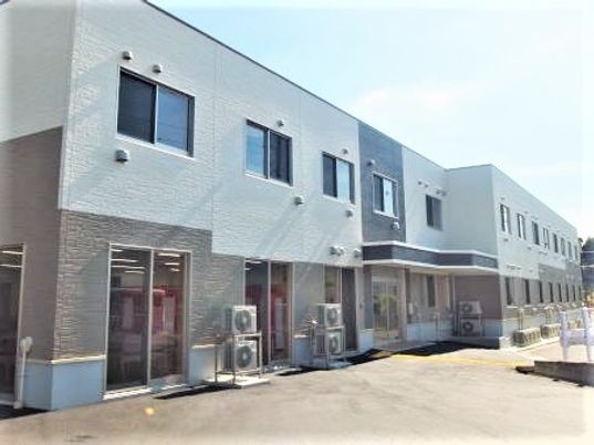 白とベージュのツートンカラーの建物の外観写真。無駄のない直背tん的なデザインの介護施設