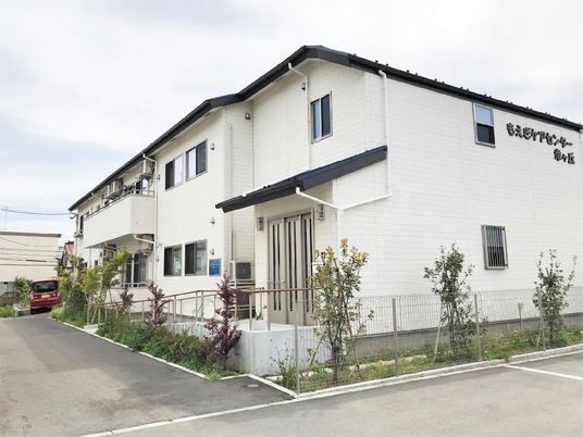 一軒家風の大きな建物の外観写真。白を基調にした壁とスロープ付きのエントランスが写っている