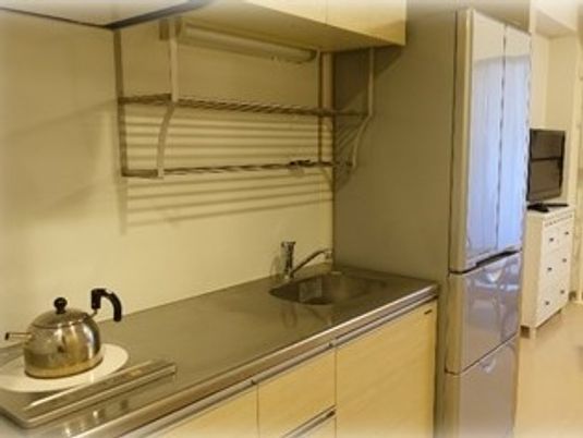 小さなキッチンスペースと冷蔵庫がある様子。お茶を沸かす程度の設備