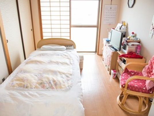 ベッドと生活用品が並べられている施設内の居室の様子。小さなワンルームタイプ