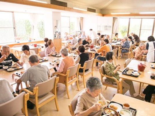 広い食堂で食事している高齢者の様子。多くの人がくつろいでいる写真