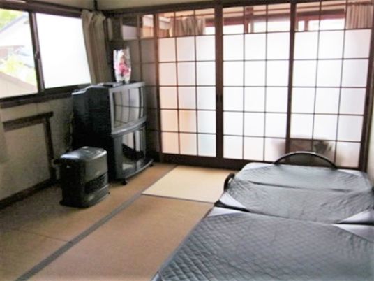 すりガラスがある畳の部屋。テレビや介護用ベッドが置いてある住まい