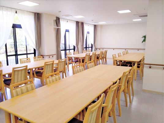 木製の長いダイニングテーブルが複数並べられた食堂は窓が大きく日当たり良好。