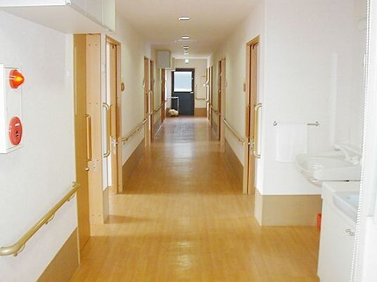 まっすぐな廊下の両サイドに手すりが付き、居室のドアも並んでいる。手前には車いす対応の洗面所もある。