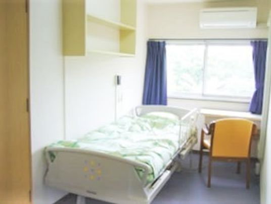 介護用ベッドと小さな机といす、エアコンが置いてある小さなワンルームの様子