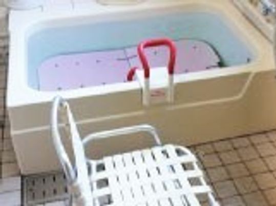 立ち上がり用の手すりとシャワーチェアが置いてある施設内の個別浴室の様子