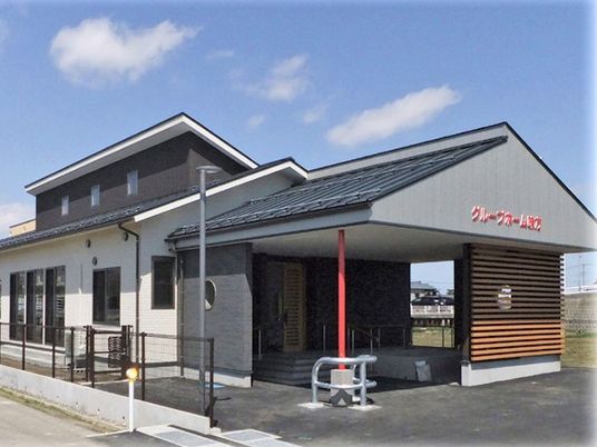 雨除けのエントランス部分があるグループホーム味方の建物。天気が良い日に移した外観写真