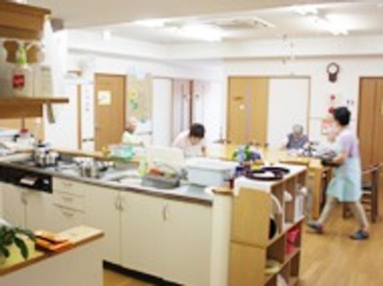 キッチンスペースとリビングの様子。施設スタッフと高齢者がくつろいでいる写真