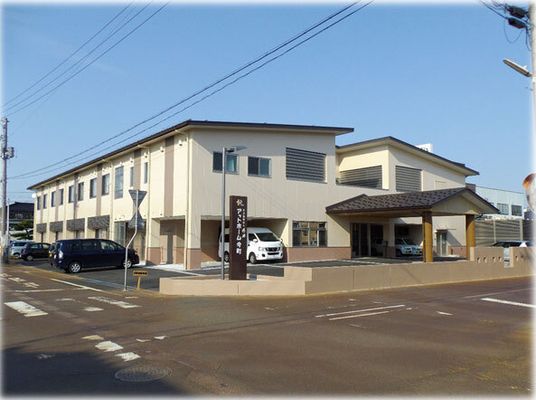 ２階建ての建物は白い外壁に屋根が付き、敷地内には駐車スペースもあり、日当たりのいい場所に建っている。