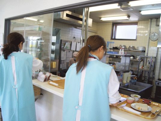 施設内のキッチンで食事を用意している様子。施設内のスタッフが働いているシーン