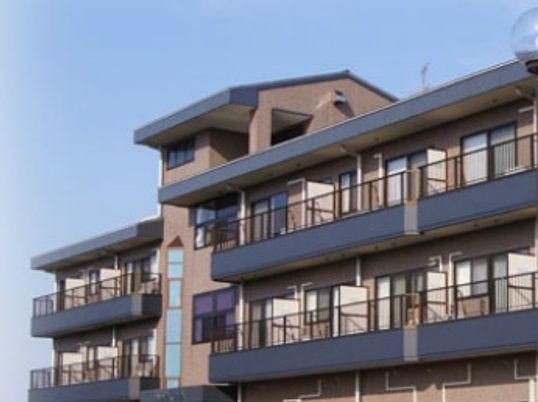 鉄骨造の建物の外観写真。個室が並びベランダにつながる窓がある様子がわかる写真