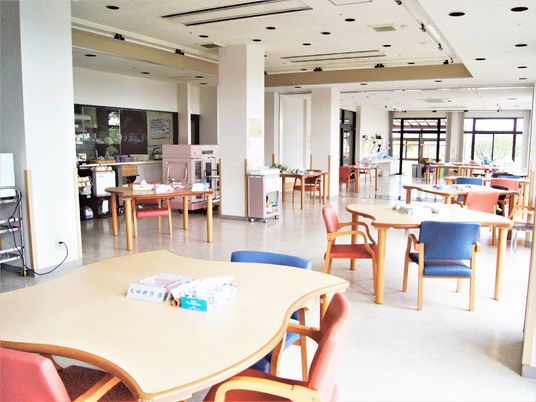 開放的なホールに四人掛けのテーブルと椅子が複数組並んでいる様子。オールバリアフリーの施設内の様子