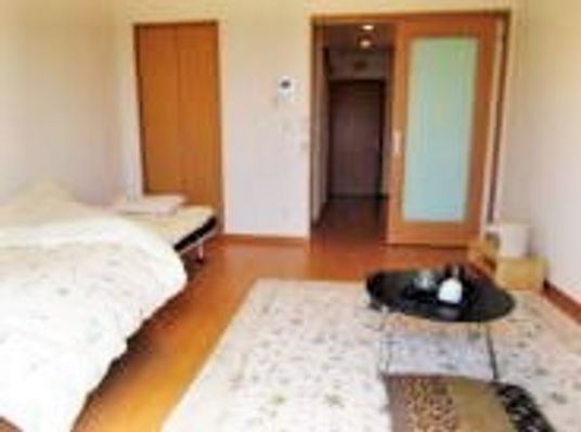 ベッドやテーブルが置かれている施設内の居室。ワンルームタイプの部屋の写真