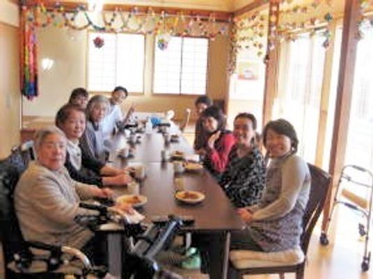 施設内の大きめのテーブルに並んでいるスタッフと利用者sの写真