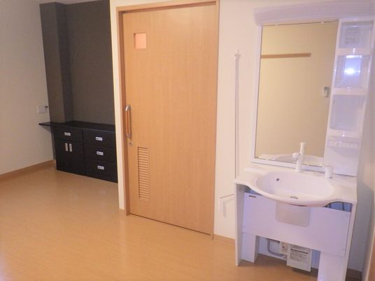 施設の居室内に備え付けられている設備と空間の写真。右側に洗面台がある様子