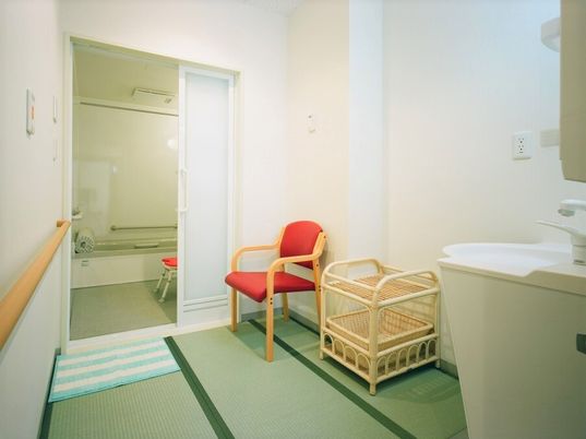 休憩用のイスと脱衣用かごが置いてある個別浴室の様子。手前に洗面台があるスペース