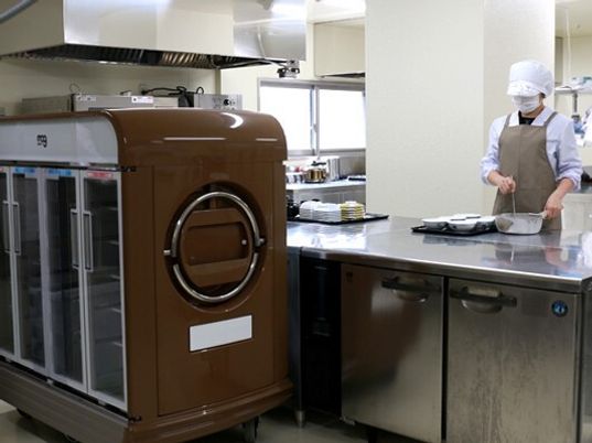 食事を作る厨房と保温・保冷配膳車の写真。スタッフが食事を作っている様子