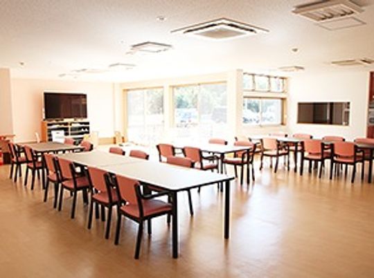 テーブルと椅子が並ぶ食堂のようなスペース。奥のほうにテレビ、窓が付いている様子