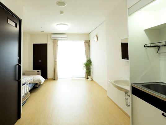 奥の方に窓がある施設内の居室。手前にトイレとキッチンスペースがある