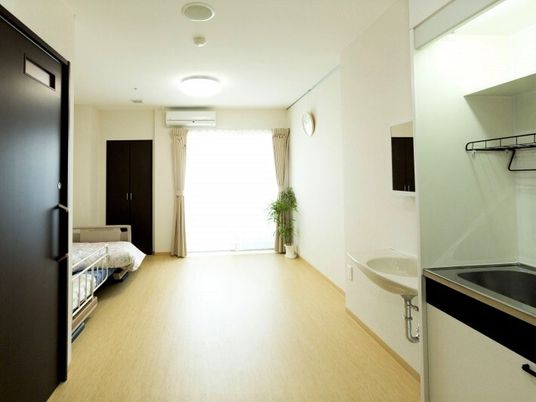 奥の方に窓がある施設内の居室。手前にトイレとキッチンスペースがある