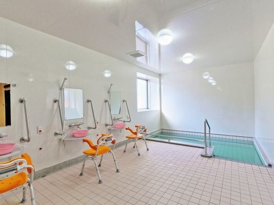 プールのような浴槽とシャワーチェア、手すりがついている施設内の浴室の様子