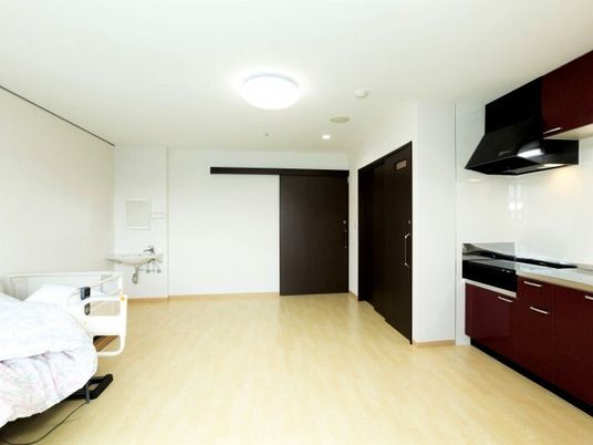 右側にキッチンやトイレのスペース、左側にベッドが置いてある施設内の居室