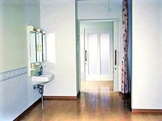 居室内の洗面台と入り口を写した写真。トイレらしき設備があるのが見えている