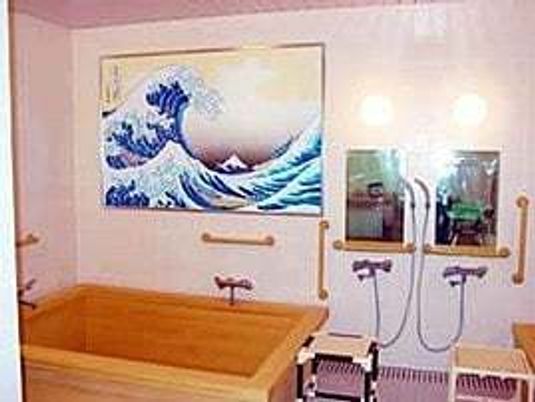 絵画のようなものが掲げられている浴室。シャワーチェアや手すりがある高齢者用の浴室