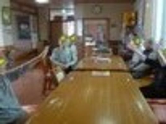 室内でラジオ体操を行う入居者。座ってしているため車いすを利用している人にも無理なく参加してもらえる。