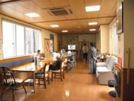 窓が大きく明るい共有スペース。入居者はテーブルやソファなど、思い思いの場所で過ごしている。