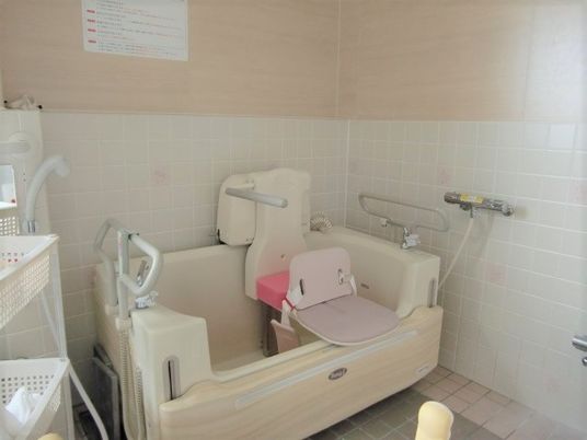 ピンクと白のタイルが貼られた明るい浴室。介護度が高い方のため機械浴もある。