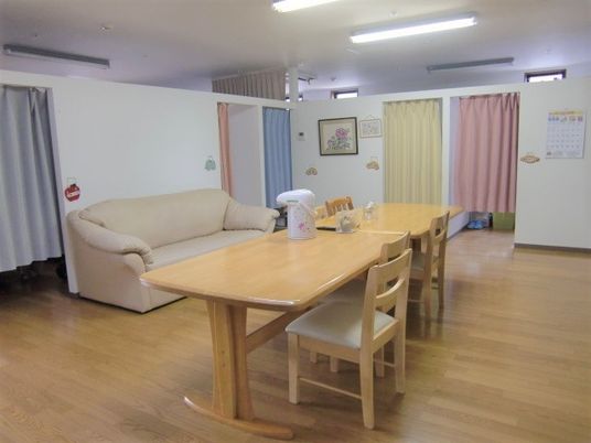 カーテンが付けられた部屋が複数あり、その中央にダイニングテーブルとソファが置かれている。