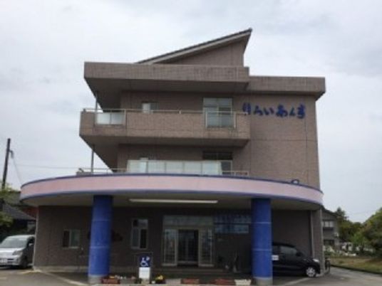 ３階建ての形に特徴がある建物。入り口付近に雨除けがついている様子