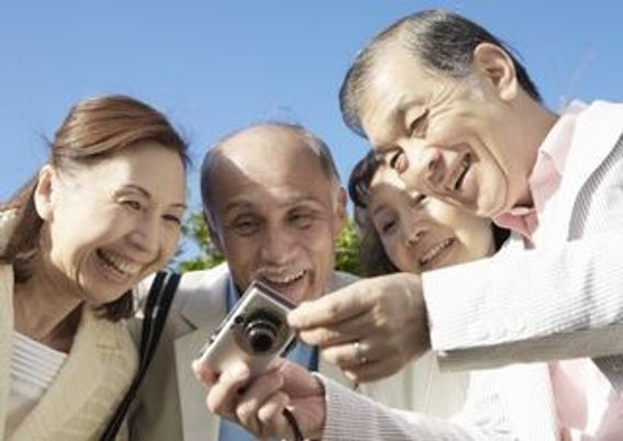 デジカメの画像を見ながら微笑んでいる男女。楽しそうに笑っている高齢者のグループ