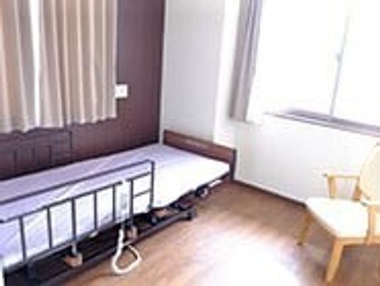 介護用ベッドやいすが置かれたフローリングの居室には大きな窓が付いている。