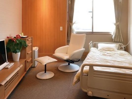 ベッドやテレビ、チェアなどが置かれた居室はカーペット敷きで大きな窓が付いている。