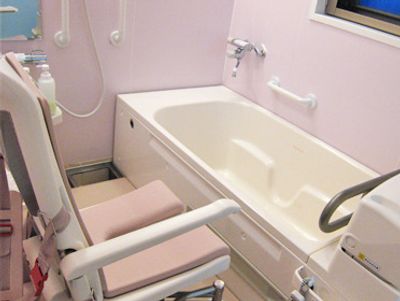 リフト付きの白い浴槽が置かれた浴室の壁には、手すりやシャワーが付いてる。