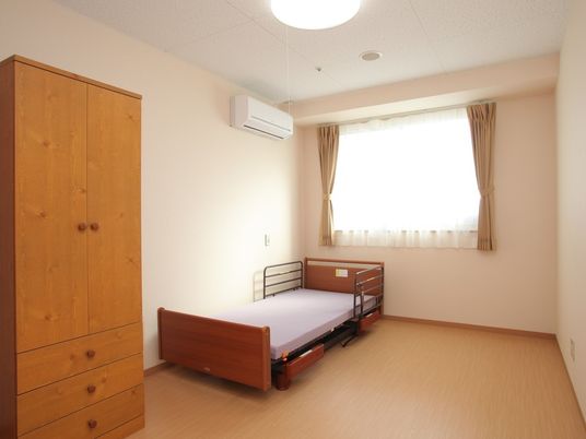 収納家具やベッド、エアコンがついた広々とした居室。