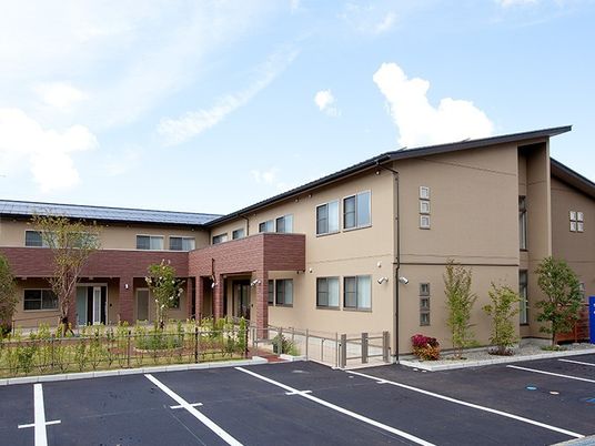 2階建ての建物はブラウン系で庭園や駐車スペースもある。