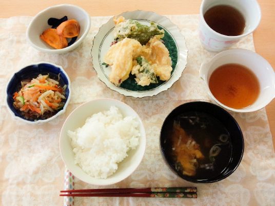 ランチョンマットの上には白いご飯、みそ汁、天ぷらや天つゆ、野菜の和え物などが並んでいる。