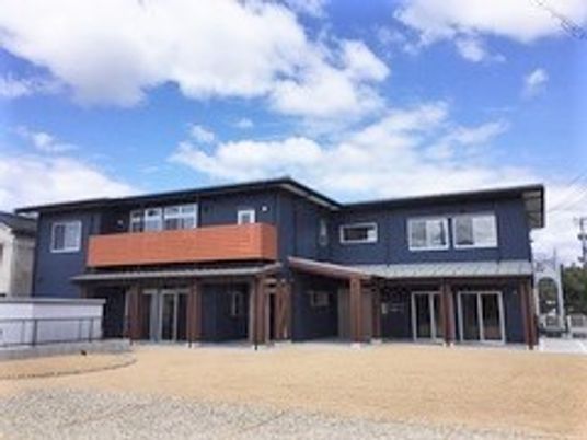 2階建ての建物はブルー系で、２階部分にベランダが付いている。
