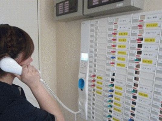 スタッフがホワイトボードを見ながら話している様子。施設内のスタッフルーム