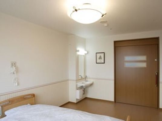 緊急通報装置が付いた部屋には介護ベッドや車いす対応の洗面所があり、大きなスライドドアが付いている。