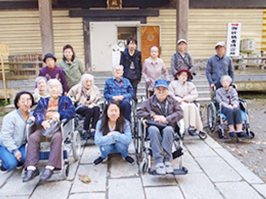 高齢者たちとスタッフが一緒に外出を楽しんでいる様子。車いすの利用者も多くいる。