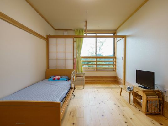 介護ベッドやテレビが設置されたフローリングの居室には障子も設置され、和の雰囲気がある。